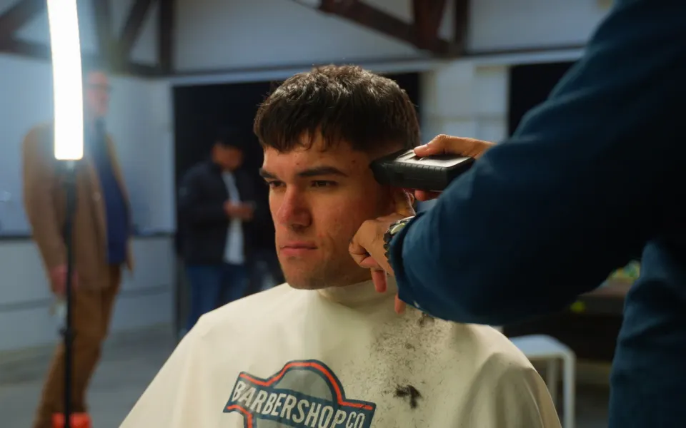 Barber running clippers through a client's hair on the BarberShopCo shop floor