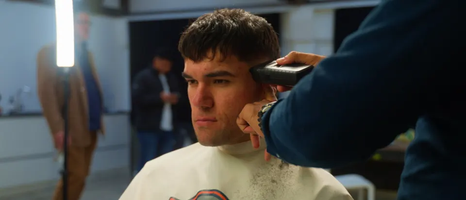 Barber running clippers through a client's hair on the shop floor